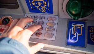 Mano che digita il pin al Bancomat