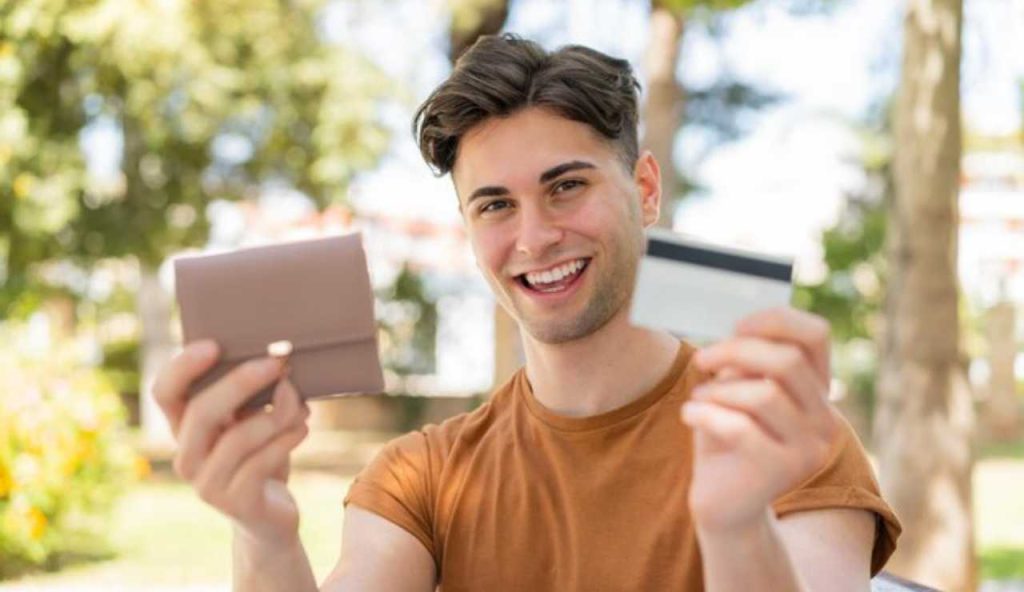 Giovane uomo felice con portafogli e bancomat